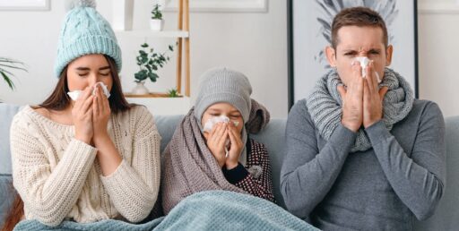 Française, famille malade toussant et ayant le nez bouché, illustrant symptômes grippaux ou rhume, en intérieur.