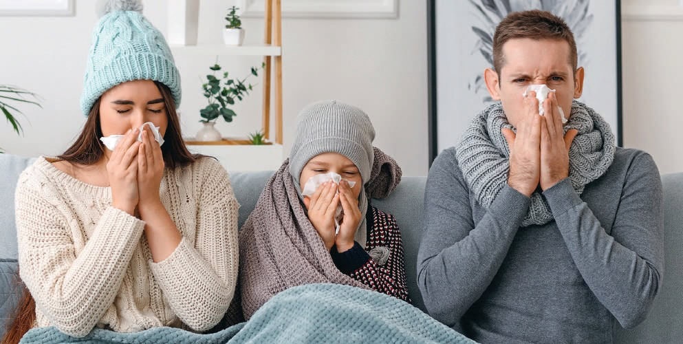 Française, famille malade toussant et ayant le nez bouché, illustrant symptômes grippaux ou rhume, en intérieur.