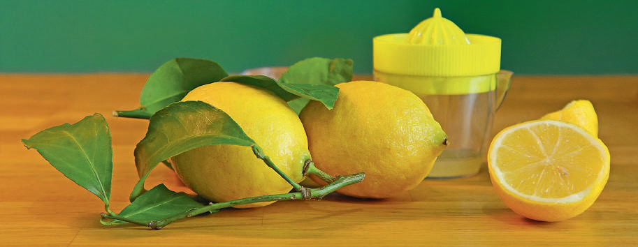 Citrons frais avec feuilles vertes et presse-agrumes jaune, parfaits pour des recettes saines ou des boissons rafraîchissantes.