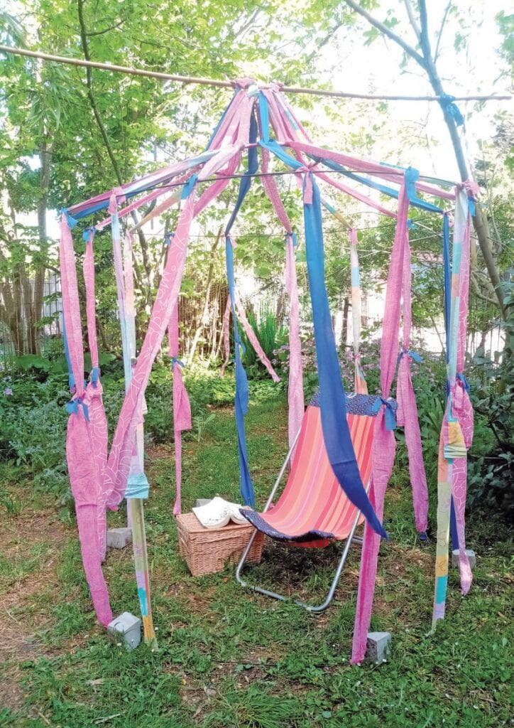 Balancelle de jardin colorée avec structure en bois, idéale pour se détendre en extérieur. Parfaite pour profiter du soleil, lire ou se relaxer dans un espace vert.