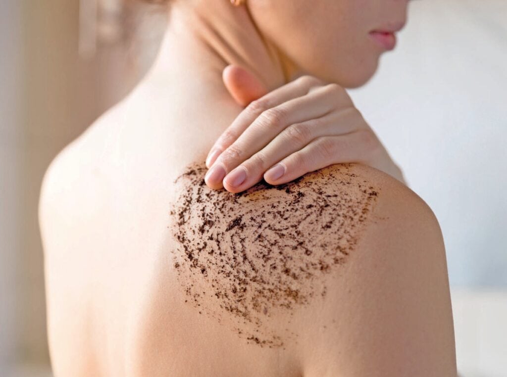 Femme appliquant une exfoliation naturelle sur l'épaule pour une peau saine et revitalisée, illustrant les soins de la peau chez Rebelle Santé.