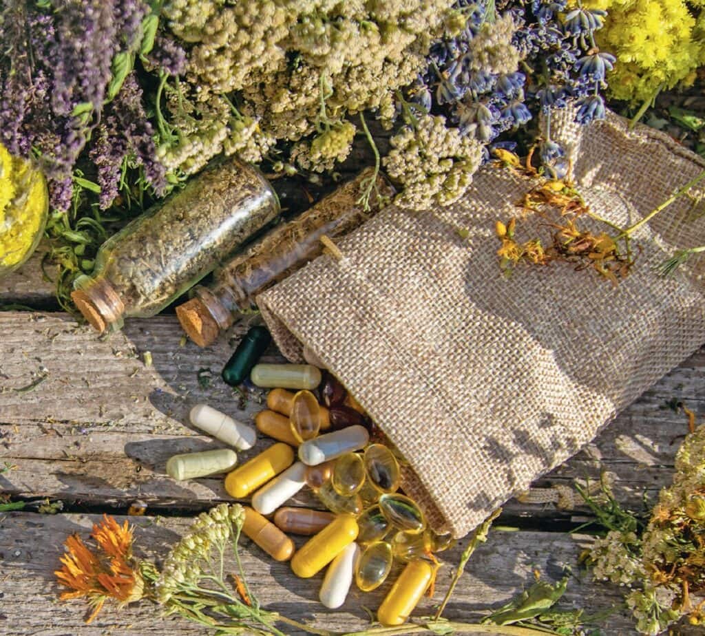 Collection de capsules, fioles et plantes médicinales bio sur une surface en bois, évoquant la santé naturelle et le bien-être.