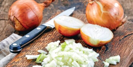- Oignons frais et coupés en dés avec couteau sur planche en bois.