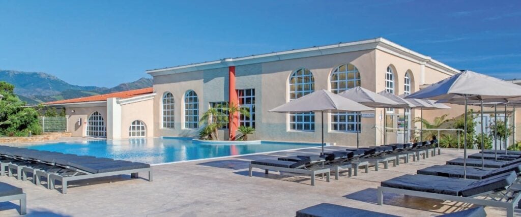 Piscine extérieure moderne avec transats, parasols et vue sur la montagne, idéale pour la détente et le bien-être dans un cadre élégant et relaxant.