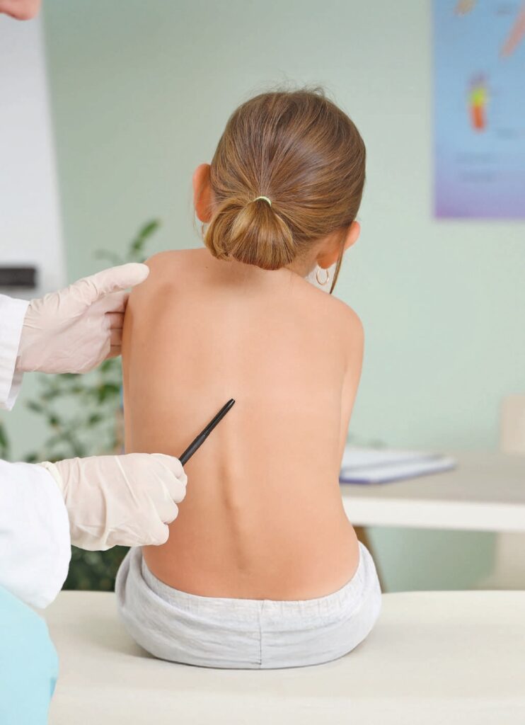 Enfant recevant une injection de vaccin contre la grippe par un professionnel de santé, assise sur une table d'examen dans un cabinet médical.